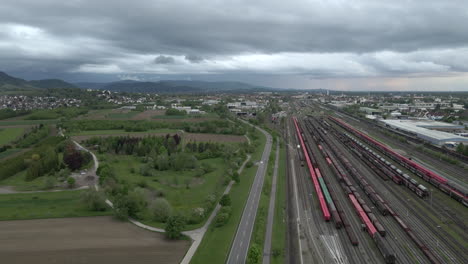 Road-with-cars-next-to-railroad-with-trains,-cityscape-in-background