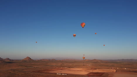 Aerial-view-of-many-hot-air-balloons-flying-over-Arizona-landscape