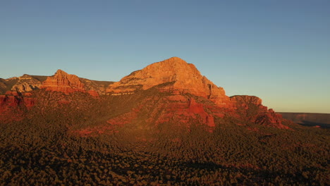 Aerial-flying-backwards-over-red-rocks-at-sunset
