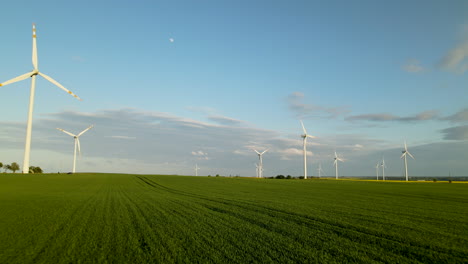 Vista-Aérea-Del-Campo-Verde-De-Verano-Con-Turbinas-De-Energía-Eólica-Que-Generan-Energía-Renovable-Limpia-Para-El-Desarrollo-Sostenible,-Pueblo-De-Lebcz,-Vuelo-Trasero-De-Drones-De-Polonia