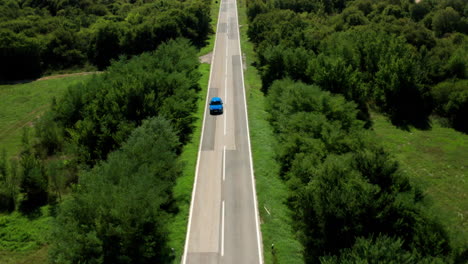Coche-Azul-Conduciendo-Por-La-Carretera-Entre-árboles-Verdes-Durante-El-Día-En-Istria,-Croacia