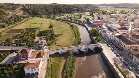 Aerial-dolly-shot-over-the-historic-town-of-Silves-in-Portugal,-showing-the-river-and-bridge-on-a-bright-sunny-day