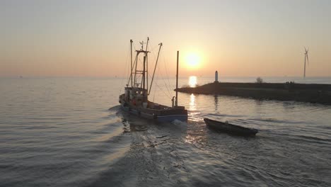 Fischerboot-Fährt-Bei-Sonnenaufgang-Mit-Hintergezogenem-Rettungsfloß-Aufs-Meer-Hinaus