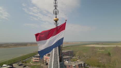 Dutch-country-flag-waving-in-wind-on-church-bell-tower-in-rural-village