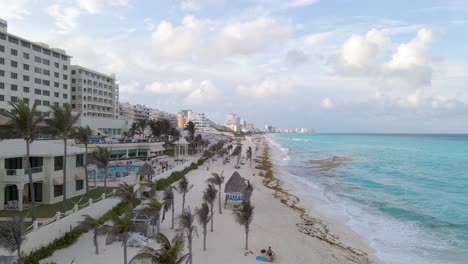 Vista-Aérea-De-Una-Hermosa-Playa-Con-Olas-Y-Palmeras-En-Cancun-Mexico,-Tiro-Panorámico