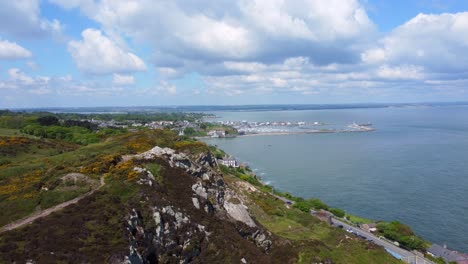 Aerial-reveal-footage-of-Howth-town-from-behind-rocky-hills
