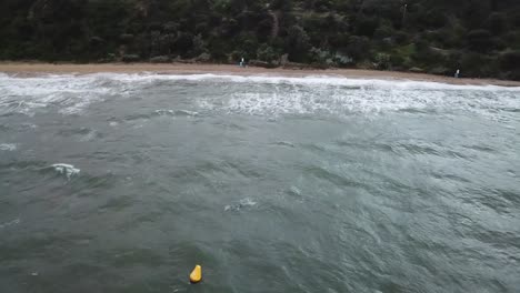 Drone-aerial-over-ocean-Melbourne-wavy-windy-cloudy-man-swimming-on-beach
