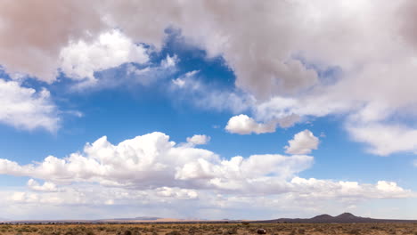 Clouds-in-abstract-shapes-blow-across-the-blue-sky-over-the-barren-land-of-the-Mojave-Desert---static-time-lapse