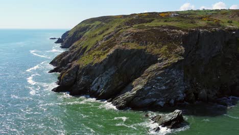 Aerial-view-of-rocky-coast-and-cliffs-with-flying-seagulls-in-bright,-sunny-day