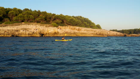 Hombre-En-Kayak-En-El-Mar-Adriático-Al-Atardecer-Cerca-De-La-Playa-De-Rocas-De-Gaviota-En-Pula,-Croacia