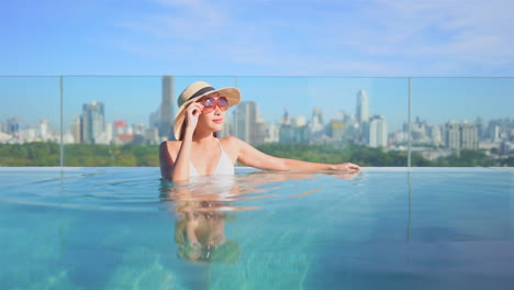 Asian-woman-relax-in-infinity-edge-pool-with-Bangkok-cityscape-in-background