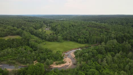 Aerial-orbit-shot-of-plush-green-countryside,-and-a-drying-creek-bed
