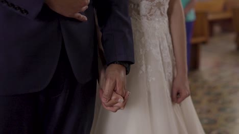 couple-holding-hands-in-the-church-on-their-wedding-day