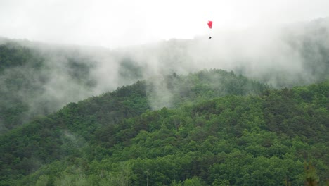 Extreme-paragliders-slowly-descending-over-the-mountain-which-vaporizing-after-the-rain-in-Danyang,-South-Korea