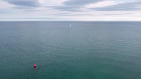 Lone-sailboat-and-red-buoy-in-beautiful-clear-turquoise-blue-fresh-water
