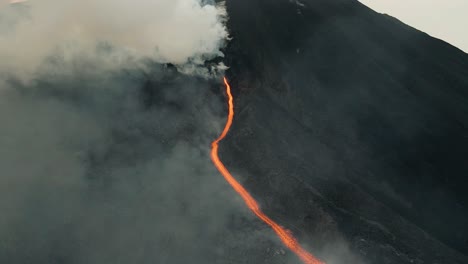 Drone-aerial-flying-through-clouds,-beautiful-landscape-of-lava-flowing-from-Pacaya-volcano-eruption-in-Guatemala