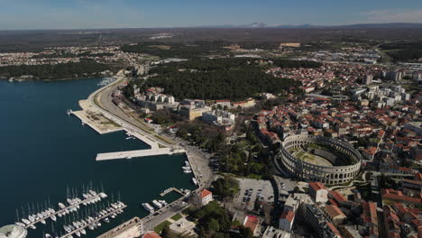 Aerial-of-Pula-Arena-and-marina-with-mountains-in-the-background