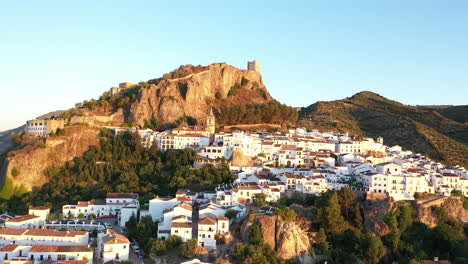 AERIAL---Cityscape-of-Zahara-de-la-Sierra,-Cadiz,-Spain,-wide-shot-lowering