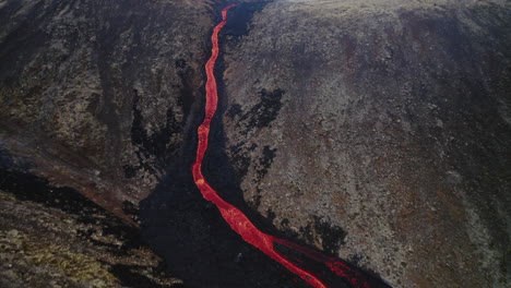 Aerial-View-Above-Volcanic-Lava-Stream-Flowing-Through-Rocky-Valley