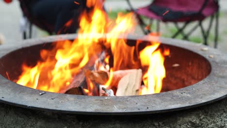 Firewood-being-added-to-Burning-Flames-of-Campfire-in-Fire-Pit,-Static