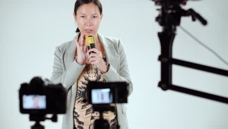 A-female-Asian-talk-show-host-does-a-microphone-test-and-sound-check-before-recording-her-program---behind-the-scenes-view