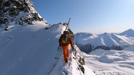 Mountain-climber-hiking-in-deep-snow-on-a-ridge-at-a-mountain-peak