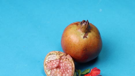 Red-ripe-pomegranates-on-blue-background,-copy-space,-top-view