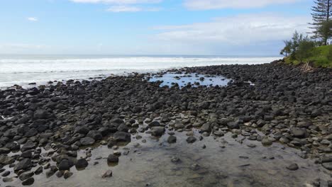 Rocks-At-The-Shoreline-Of-The-Burleigh-Beach-In-Queensland,-Australia-At-Daytime