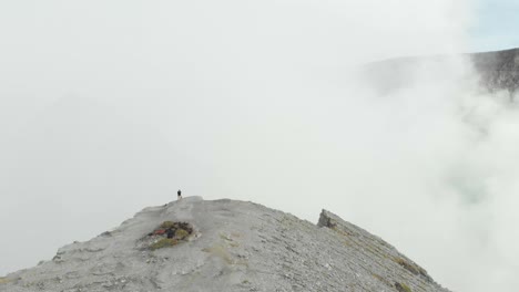 Person-exploring-edge-of-Ijen-volcano-with-thick-sulfur-smoke-from-crater