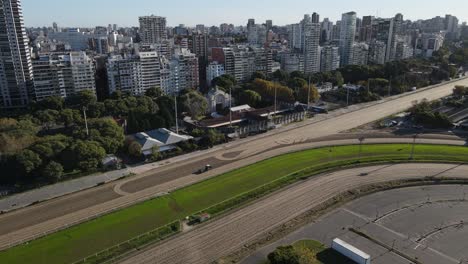 Aerial-shot-of-soil-compactor-preparing-race-course-of-Buenos-Aires-in-front-of-gigantic-cityscape-in-summer