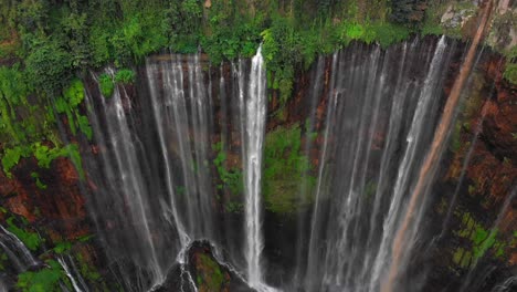 Thousand-waterfalls-flowing-from-steep-wet-cliff-in-Java-jungle,-aerial