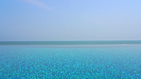 Blaues-Wasser-Eines-Infinity-Pools-Mit-Meerblick-Am-Horizont