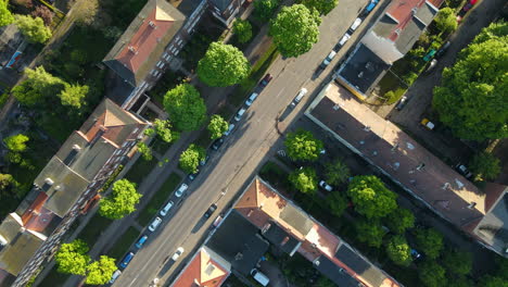 Aerial-Drone-Roll-Around-Vehicles-Parked-On-Roadside-Along-with-Buildings-On-A-Sunny-Day-In-Gdansk,-Poland---top-down-view