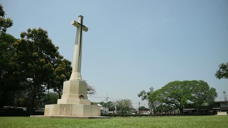 HD-statische-Aufnahme-Des-Gedenkfriedhofs-Des-Zweiten-Weltkriegs-Mit-Hohem-Kruzifix-Denkmal-Auf-Einem-Friedlichen-Friedhof-In-Kanchanaburi,-Thailand