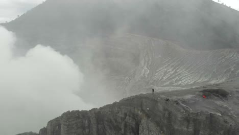 Adventure-traveler-enjoys-extreme-view-of-Kawah-Ijen-volcano,-sulfur-smoke