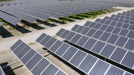 Miles-De-Paneles-Solares-Que-Producen-Energía-Renovable-En-Una-Granja-Solar-Revelados-En-Un-Vuelo-Aéreo-Bajo-Hacia-Atrás