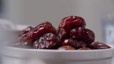 Hand-Picks-Up-Sweet-Date-Fruit-From-Heap-In-A-White-Bowl