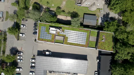 Top-down-aerial-of-solar-panels-on-a-green-rooftop---drone-lifting-up