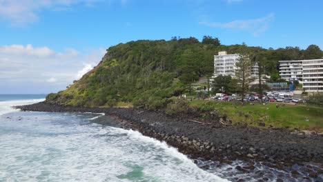 Panorama-Of-Beachfront-Accommodations-At-The-Shoreline-In-Summer-With-White-Waves-Splashing-On-Rocky-Burleigh-Hill-In-Gold-Coast,-Queensland