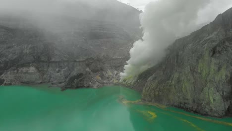 Turquoise-lake-of-Ijen-volcano-crater-with-white-sulfur-smoke-from-mine
