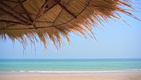 Sombrilla-De-Paja-En-La-Playa-Exótica-Tropical-Y-El-Mar-De-Fondo
