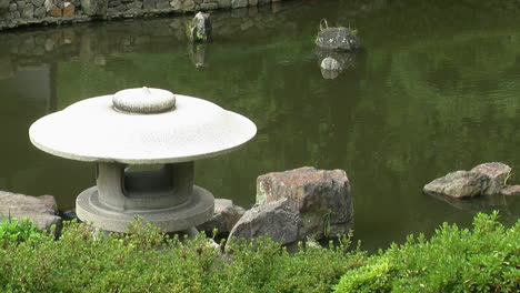 A-Japanese-snow-viewing-lantern-in-front-of-a-koi-pond