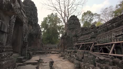 Walking-through-a-richely-decorated-but-broken-down-temple-in-Angkor-Wat,-Cambodia