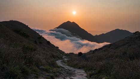 Sunset-seen-from-Sunset-Peak,-Hong-Kong-with-people-walking-the-stony-path-in-mountain