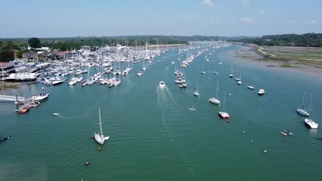 High-up-drone-shot-of-boats-entering-and-exiting-the-marina-on-a-sunny-day-in-the-south-of-england