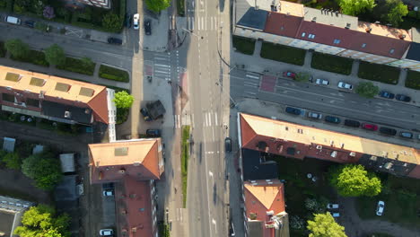 Aerial---Drone-Flying-over---One-Person-Riding-Bicycle-in-the-Morning-to-Get-to-Work-and-Passing-Crossroad-in-Residential-District-of-Gdansk-on-Summer-Sunny-Day,-Poland,-top-down-following-view