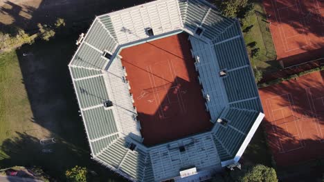 Ascending-aerial-top-down-of-tennis-court-stadium-in-Buenos-Aires-during-sun,Argentina
