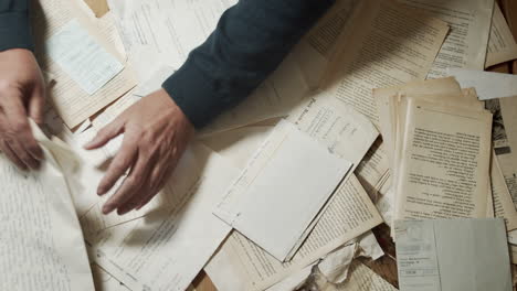 Male-hands-nervously-searching-old-documents.-Top-shot