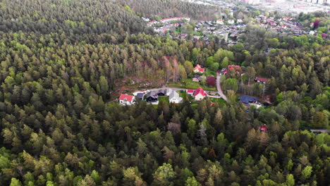 Aerial-backward-view-of-a-Nordic-neighborhood-hidden-by-a-lush-vast-forest