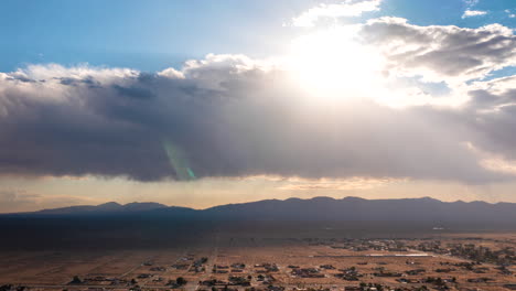 Aerial-time-lapse-over-California-City-with-the-sun-shinning-through-the-clouds-and-rays-of-sun-casting-light-and-shadow-over-the-community-in-the-valley